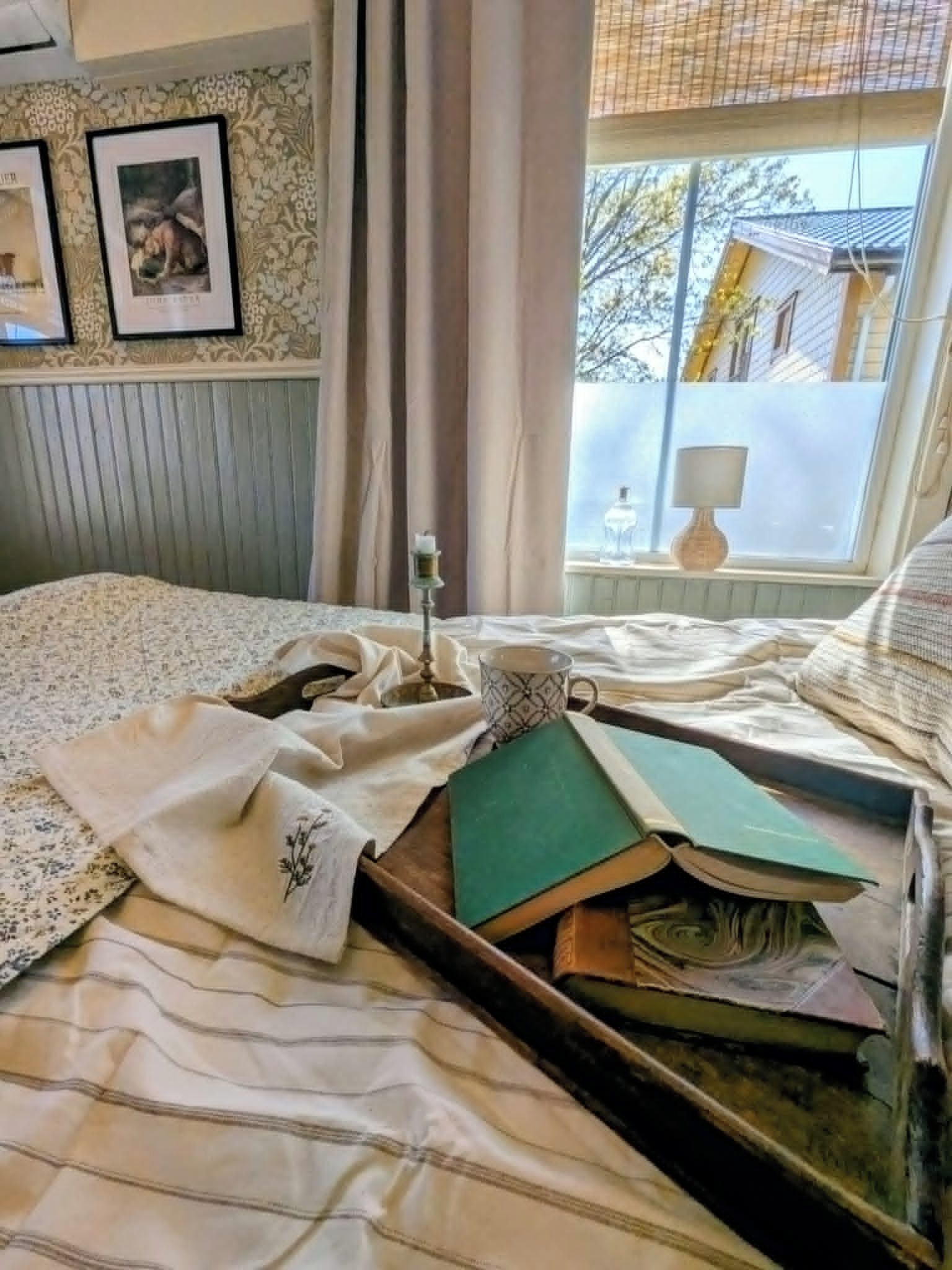 Et soveværelse med seng, et vindue med udsigt til en bygning og et natbord med lampe.