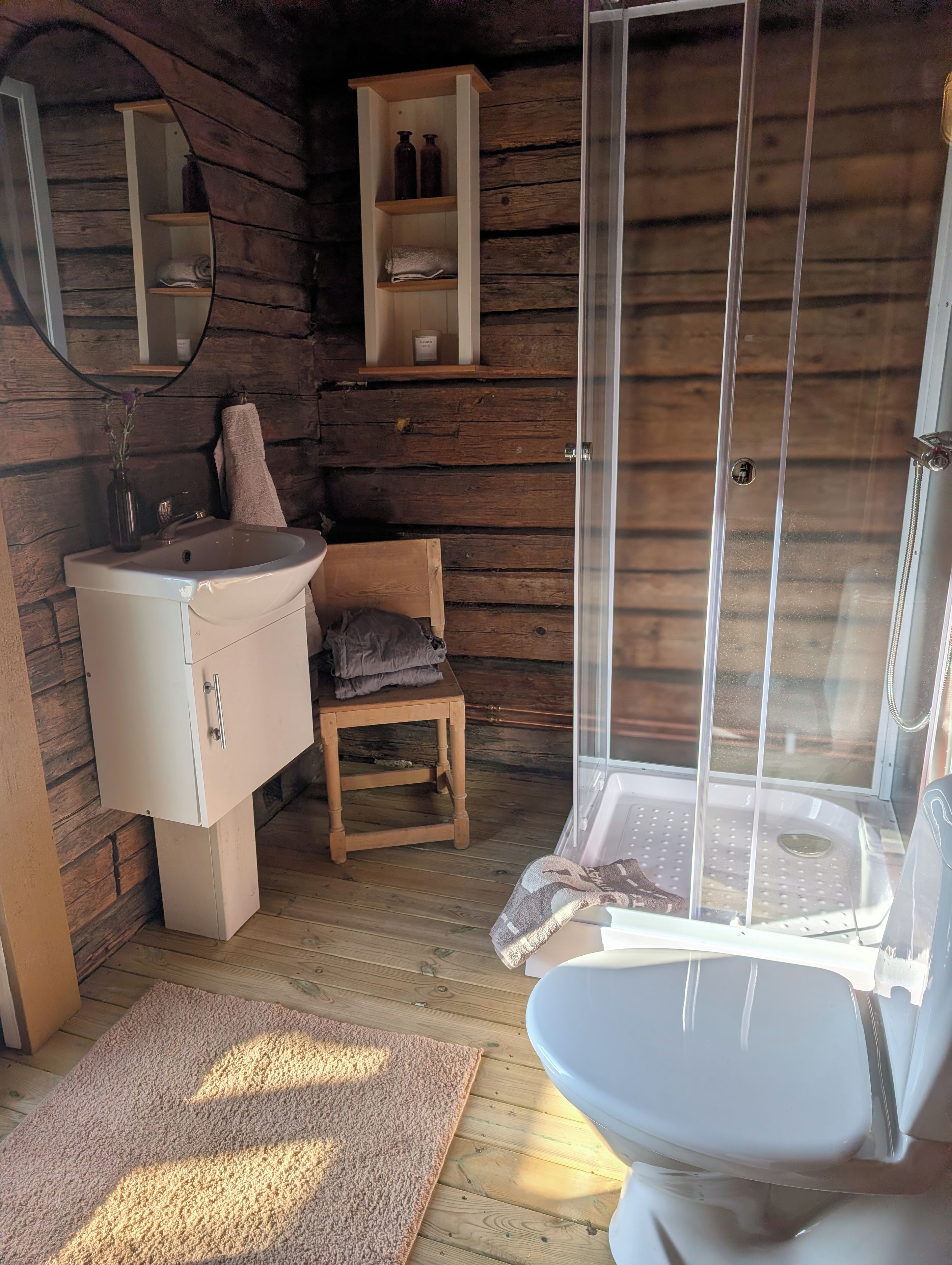Et lille badeværelse med vask, toilet og brusebad.