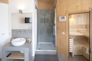 A modern bathroom with a built-in shower, a sink, and a wooden sauna area. - Cabin with 1 bedroom (St. Georgen am Kreischberg)