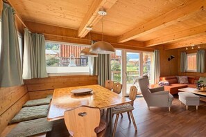Ein Holzinnenraum mit Esstisch, Sitzgelegenheiten und einer Sofaecke.