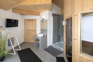 Une salle de bain moderne avec un plafond en bois, un téléviseur, un lavabo, un miroir et une cabine de douche en verre.
