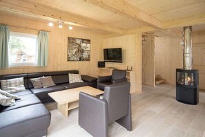 Ein modernes Wohnzimmer mit einer Sofagarnitur, einem Couchtisch, einem Kamin und einem an der Wand montierten Fernseher.