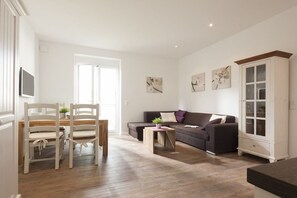 Ein modernes Wohnzimmer mit einer Couch, zwei Sesseln, einem Couchtisch und einem Schrank.