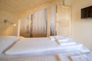 A bedroom with a bed, a wall-mounted TV, and a door leading to another room. - Cabin with 1 bedroom (St. Georgen am Kreischberg)