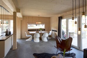 Ein modernes Interieur mit Essbereich, Küche und großen Fenstern.