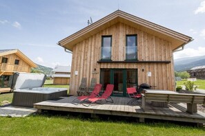 A wooden cabin with a deck, outdoor seating, and a hot tub. - Cabin with 1 bedroom (St. Georgen am Kreischberg)