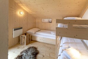 Eine Holzhütte mit einem Etagenbett, einem kleinen Nachttisch, einem Heizgerät und einem Fellteppich auf dem Boden.