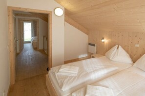 Ein Schlafzimmer mit zwei Betten, Holzwänden, einer sichtbaren Tür zu einem anderen Raum und einer Wandleuchte.