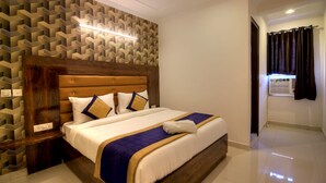 Ein Hotelzimmer mit Bett, Kopfteil, Wand mit geometrischem Muster und einem Vorhangfenster.