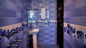 Ein Badezimmer mit Waschbecken, mehreren Wasserhähnen und einer Duschkabine.