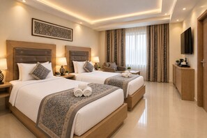 A hotel room with two beds, a television, a desk, and a large window with curtains. - HOTEL KAVYA INN  (New Delhi)