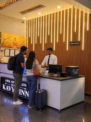 A reception desk with a wooden panel design and a sign that reads 'WE TREAT YOU LIKE FAMILY'. - HOTEL KAVYA INN  (New Delhi)