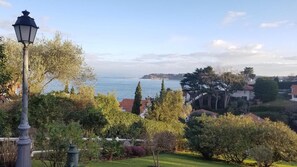 A coastal landscape with a lamp post, trees, and houses in the background. - Between Land & Sea – Ocean View and Private Garden in Ciboure (Ciboure)