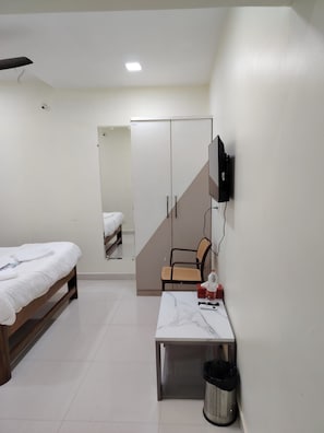 Ein Schlafzimmer mit einem Bett, einem Schreibtisch, einem Stuhl, einem Fernseher und einem Kleiderschrank.