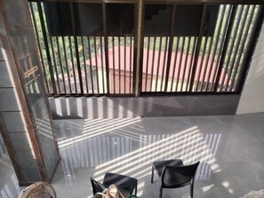 A balcony with a view of a red-roofed building and greenery, two black chairs, and a 'No Smoking' sign.
