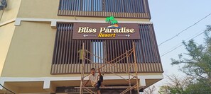 A sign for Bliss Paradise Resort with a tropical theme, including palm trees and a sun.