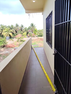 A balcony with a view of a residential area, a water tank, and a house with a red roof.