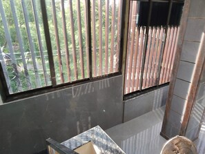 A room with a large window, a fan, and a tiled floor.