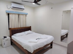 A neatly made bed with white linens, a bedside table with a phone, and a ceiling fan.