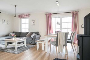 Un salon confortable avec un canapé, une table basse, une table à manger avec des chaises et une cheminée.