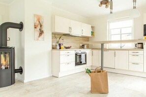 A modern kitchen with white cabinets, a built-in oven, and a black stove. - Holiday home with 2 bedrooms (Fuhlendorf)