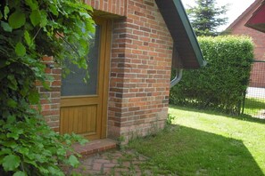 Un bâtiment en briques avec une porte en bois et un petit porche.