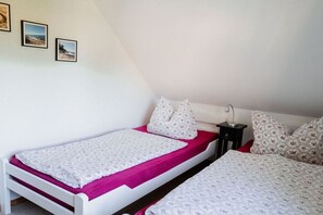 Una camera da letto con due letti singoli, un comodino e una lampada a parete.