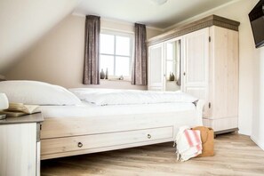 A bedroom with a bed, a nightstand, a wardrobe, and a window with curtains. - ||--------------------Reed Warbler 30------------------|| (Fuhlendorf)