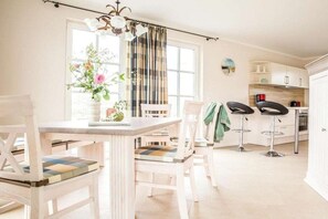A bright kitchen with white cabinets, a dining table with chairs, and two bar stools. - ||--------------------Reed Warbler 30------------------|| (Fuhlendorf)