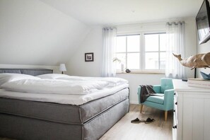 A bedroom with a bed, a desk, a chair, a television, and a window with curtains. - Holiday home with 2 bedrooms (Fuhlendorf)