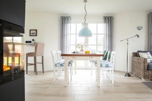 A modern kitchen with a dining table, chairs, and a pendant light. - Holiday home with 2 bedrooms (Fuhlendorf)