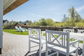An outdoor patio with white chairs and a stone wall. - Holiday home with 2 bedrooms (Fuhlendorf)