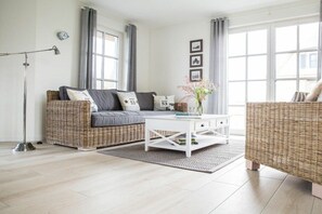 A modern living room with a sofa, coffee table, and a floor lamp. - Holiday home with 2 bedrooms (Fuhlendorf)