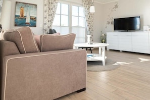 Ein modernes Wohnzimmer mit einer Couch, einem Flachbildfernseher und einem Esstisch.