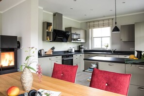 Une cuisine moderne dotée d’un îlot central, d’appareils électroménagers intégrés et d’un coin repas avec des chaises rouges.