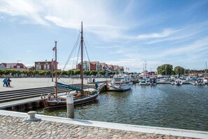 A marina with boats docked, a flagpole, and buildings in the background. - Holiday home with 2 bedrooms (Fuhlendorf)