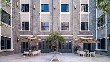 Un patio con una mesa redonda y sillas, rodeado de muros de ladrillo y amplias ventanas.