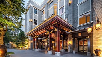 Een hotel ingang met een overdekte gang, grote ramen en traditionele decoratieve details.