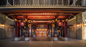 Una entrada de arquitectura china tradicional con techo de tejas, vigas de madera y faroles.
