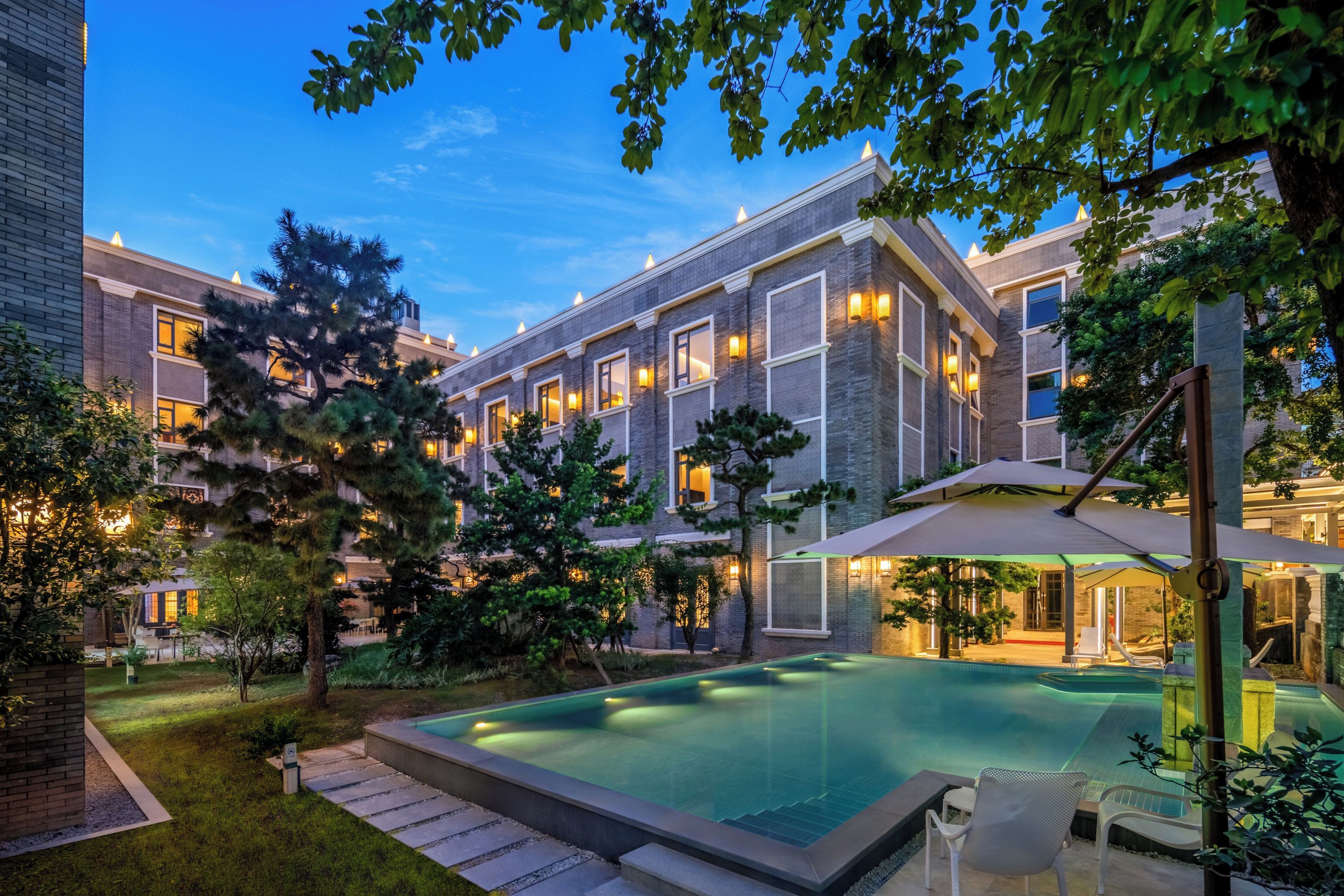 Een modern hotel met een zwembad, terras en verzorgde tuin.
