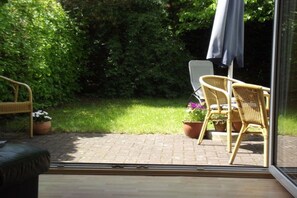Eine Terrasse mit Korbstühlen, einem Tisch und Topfpflanzen.