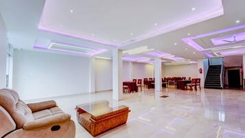 A spacious hotel lobby with a seating area, a reception desk, and a staircase leading to another floor.