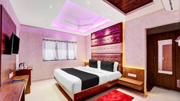 A modern bedroom with a bed, a desk, a TV, and a red rug.