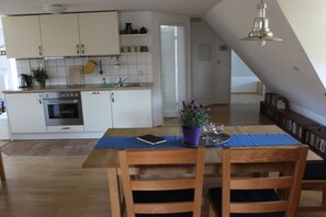 Eine moderne Küche mit weißen Schränken, einem eingebauten Ofen und einem Essbereich mit Tisch und Stühlen.