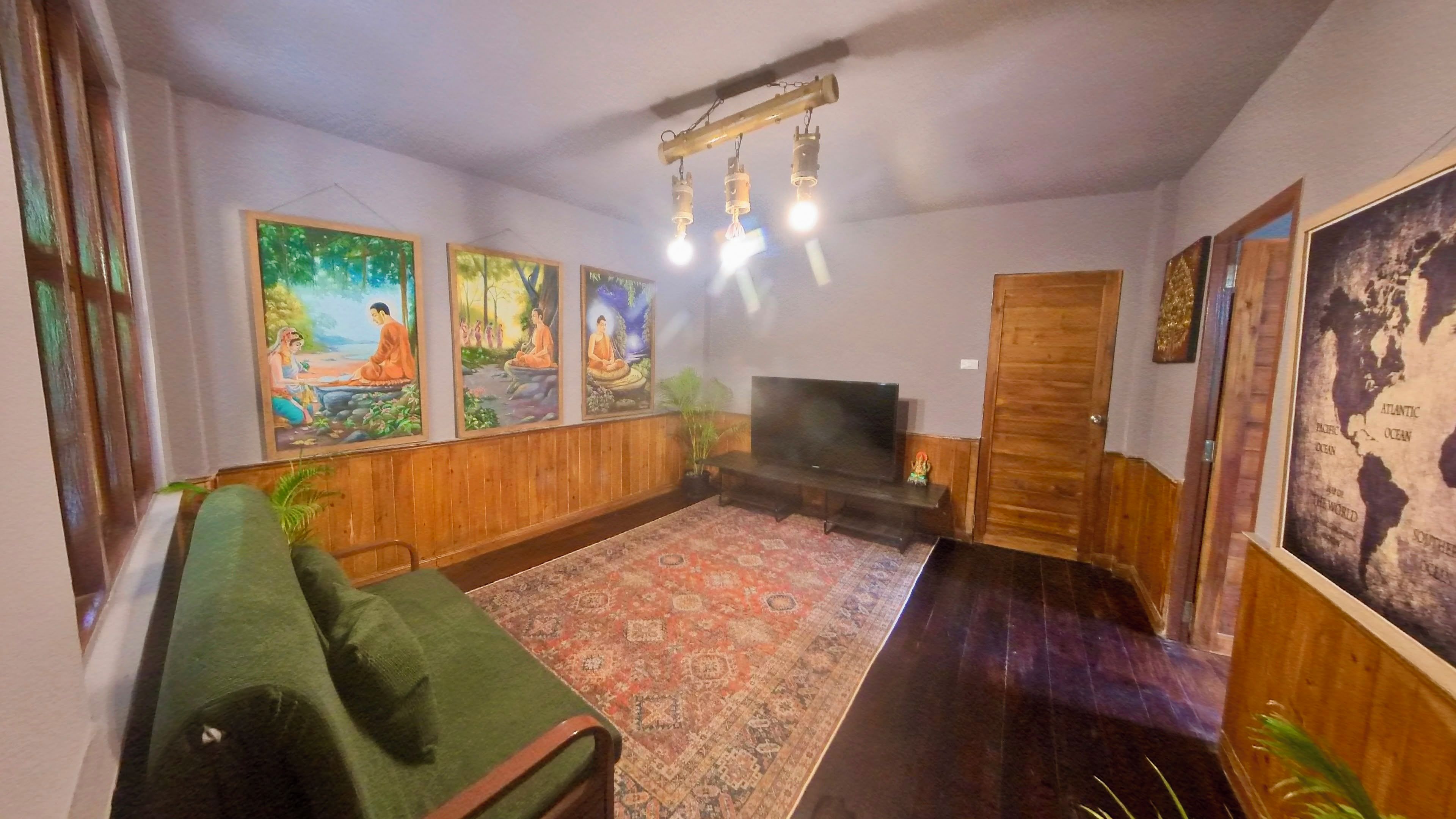 Un salon comprenant un canapé, un téléviseur à écran plat, un tapis à motifs et des tableaux accrochés au mur.