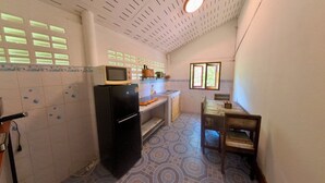 Cocina compacta con refrigerador, microondas y una pequeña mesa de comedor.