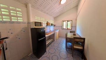 A compact kitchen with a refrigerator, microwave, and a small dining table.