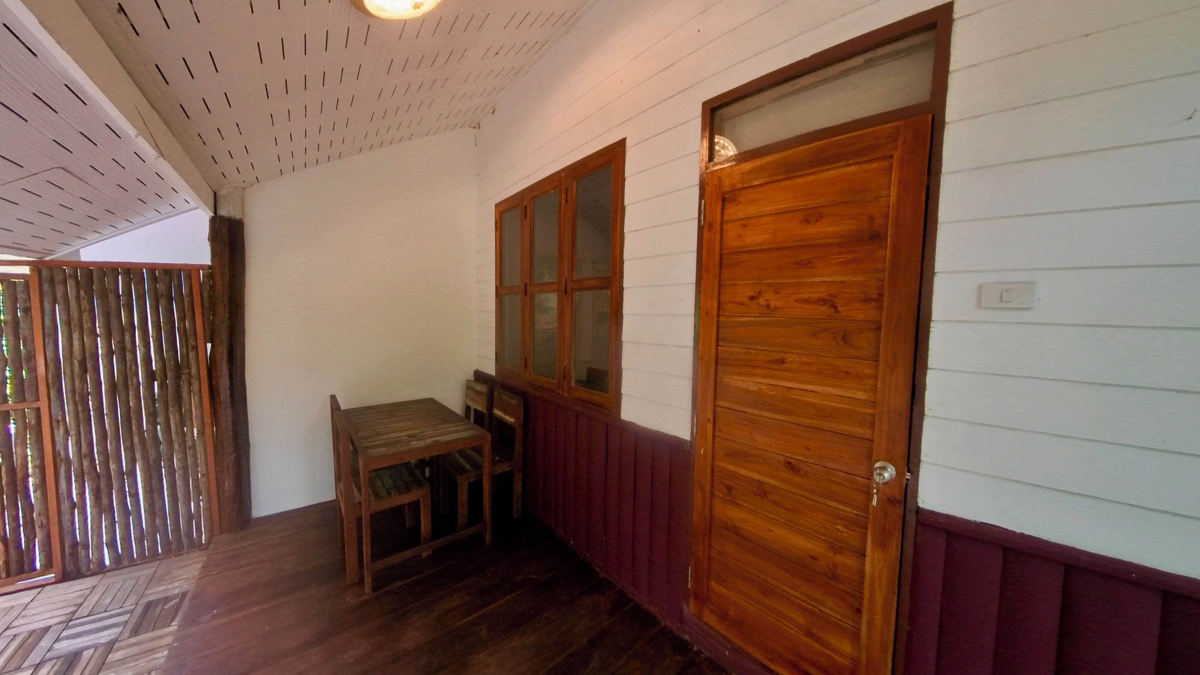 Un pasillo con puerta de madera, una ventana y una pequeña mesa.