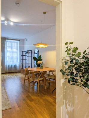 A dining area with a wooden table and chairs, a hanging pendant light, and a plant on the right. - Premium Smart Studio near Frauenkirche - 2 Beds - Parking - by RIHOME (Dresden)