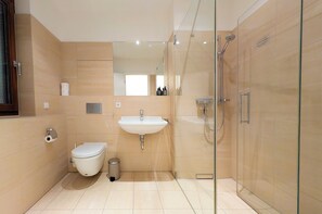 A modern bathroom with a toilet, sink, and glass-enclosed shower.